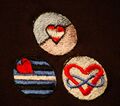 Sewable patches, the emblem on the bottom left signifies a leather fetish, the right one signifies polygamy support.